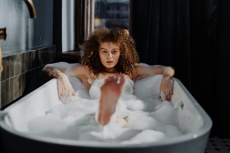 a woman taking a bubble bath in a bathtub, trending on pexels, renaissance, curly haired, sitting on top of a cryopod, bitches brew, snow on the body