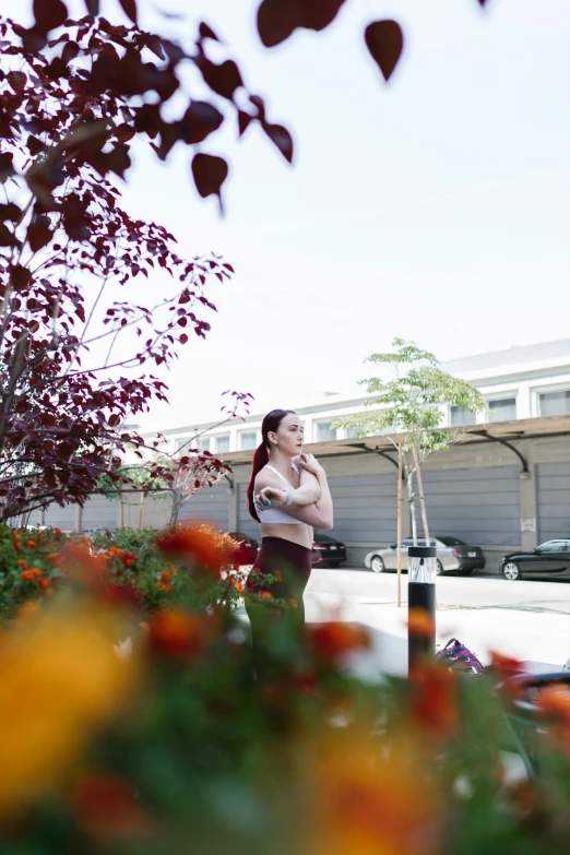 a woman standing in a flower garden talking on a cell phone, unsplash, happening, standing in a parking lot, sheryl sandberg at soulcycle, looking away from camera, from street level