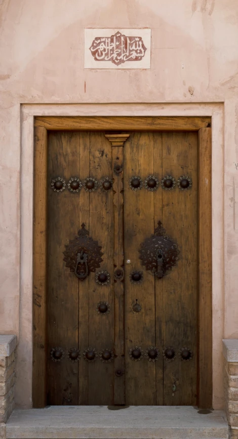 a large wooden door sitting on the side of a building, unsplash, renaissance, oman, color image, brown:-2, square