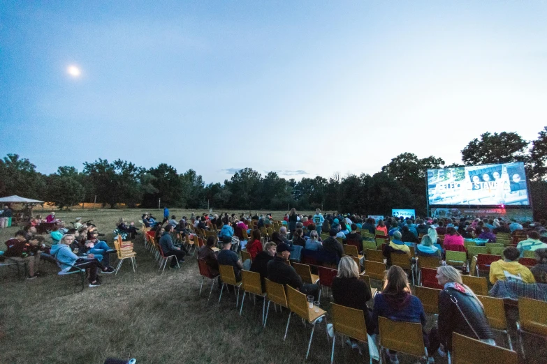 a group of people sitting in chairs watching a movie, by karlkka, happening, nature show, wide open space, instagram photo, cinestill