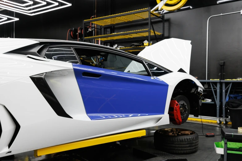 a white and blue sports car in a garage, inspired by Bernardo Cavallino, renaissance, bold lamborghini style, fully armoured, engineering bay, white mechanical details