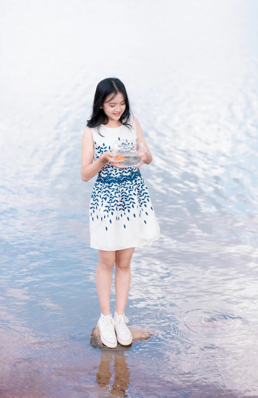 a woman standing in shallow water looking at a cell phone, inspired by Ma Yuanyu, blue-white dress, 15081959 21121991 01012000 4k, cute photograph, wearing white sneakers