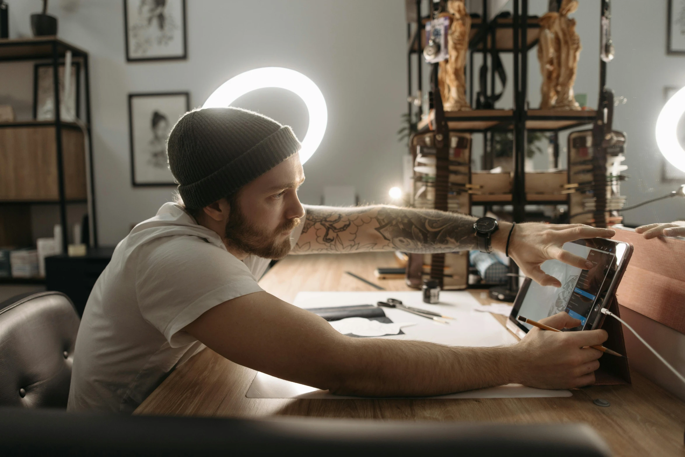 a man sitting at a desk using a tablet computer, an airbrush painting, trending on pexels, hyperrealism, glowing tattoos, selfie photo, 9 9 designs, drawing on a parchment