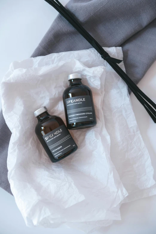 a couple of bottles of liquid sitting on top of a towel, by Nina Hamnett, unsplash, renaissance, japanese collection product, grey robe, bedhead, with black