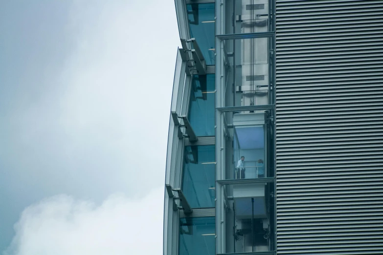 a clock that is on the side of a building, inspired by Tadao Ando, unsplash, modernism, aquamarine windows, towering above a small person, lower and upper levels, glass and steel