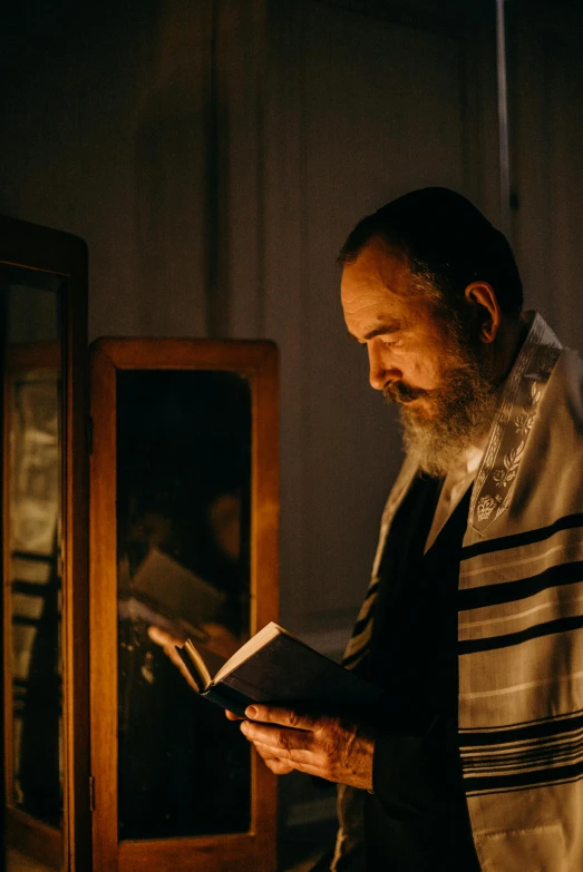 a man reading a book in front of a mirror, by Micha Klein, pexels, symbolism, sukkot, candlelit, wearing robes and neckties, hebrew