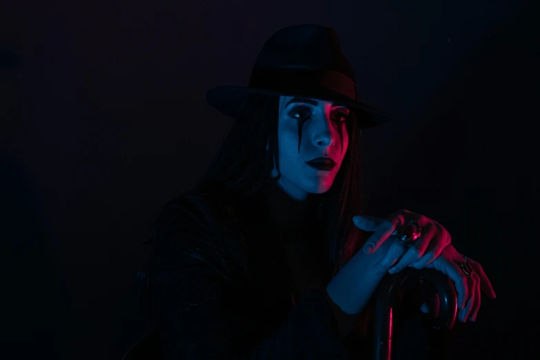 a woman wearing a hat and holding a cane, an album cover, inspired by Elsa Bleda, pexels contest winner, red lighting on their faces, cultist, shot with sony alpha 1 camera, woman vampire