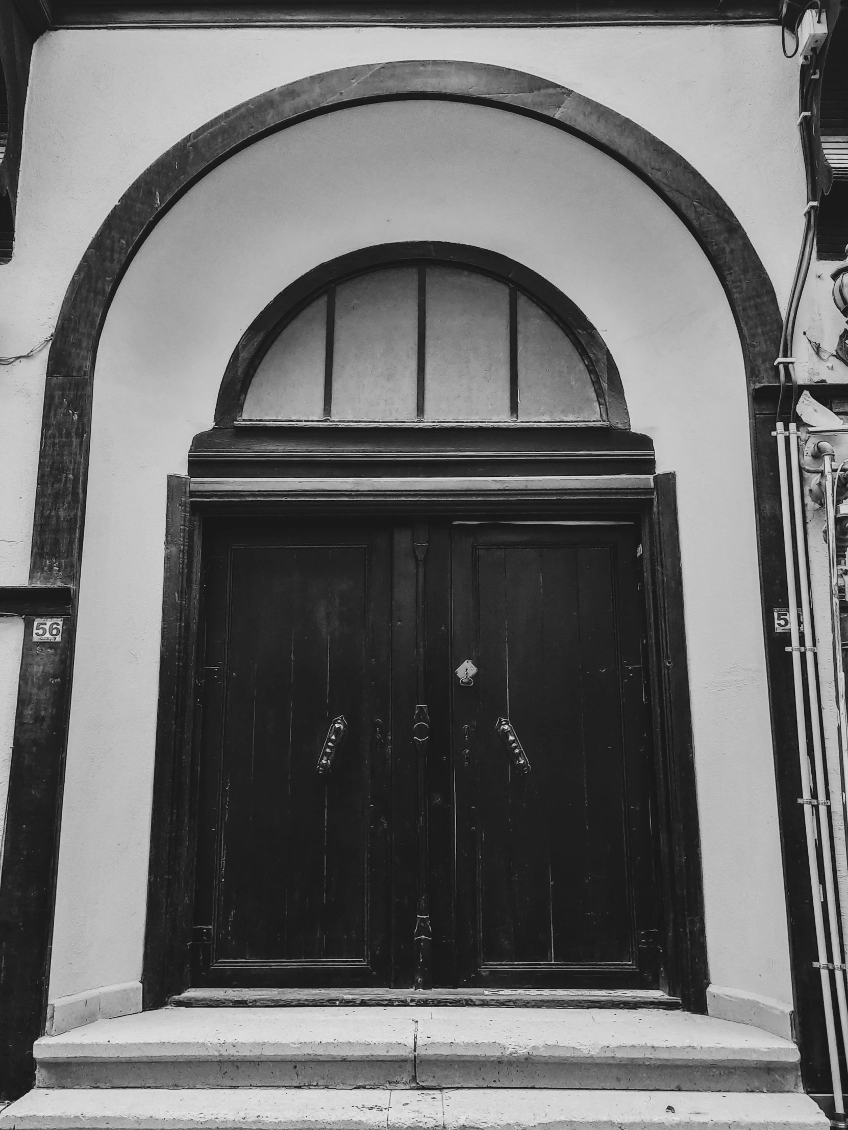 a black and white photo of a doorway, by Kristian Kreković, unsplash, rounded roof, old timey, freddy mamani silvestre facade, 3 doors