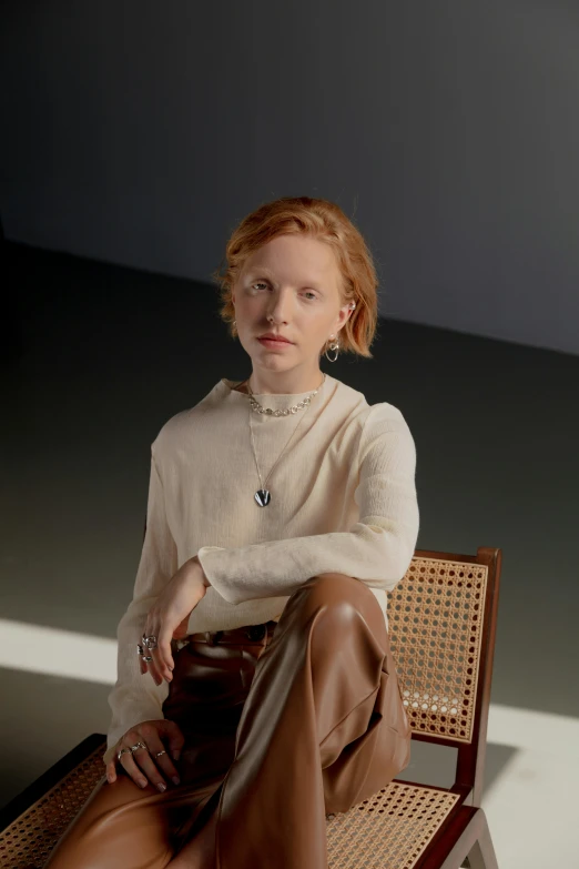 a woman sitting on top of a wooden chair, an album cover, inspired by Anna Füssli, featured on reddit, renaissance, albino white pale skin, wearing a linen shirt, amber jewelry, photographed for reuters