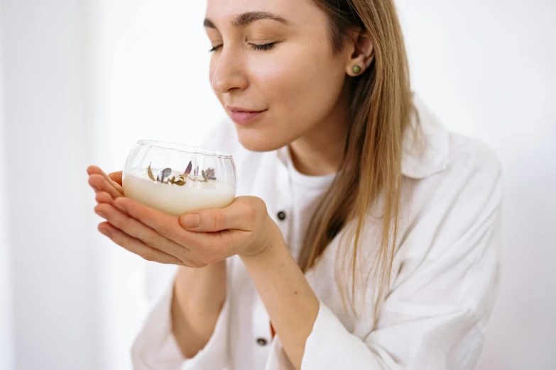 a close up of a person holding a bowl of food, floating in perfume, looking off to the side, silver small glasses, manuka