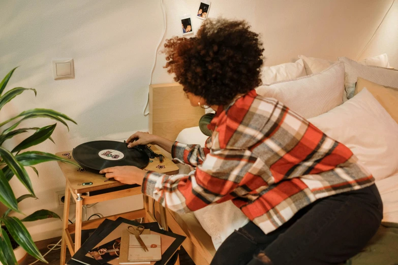 a woman sitting on a bed playing a record, pexels contest winner, funk art, over a dish and over a table, wireless headphone stand, medium shot taken from behind, youtube thumbnail