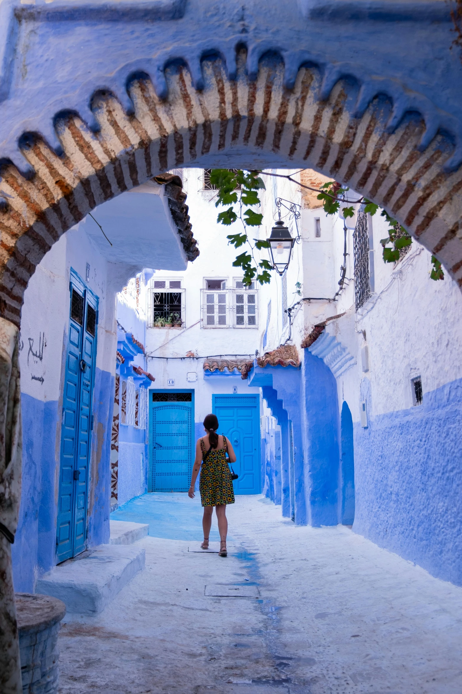 a woman walking down a narrow alley way, arabesque, blue and white colour scheme, canopies, blue sand, full of colour