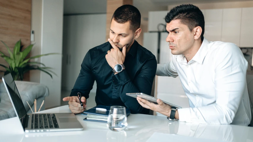 two men sitting at a table looking at a laptop, pexels contest winner, 9 9 designs, looking serious, te pae, workers