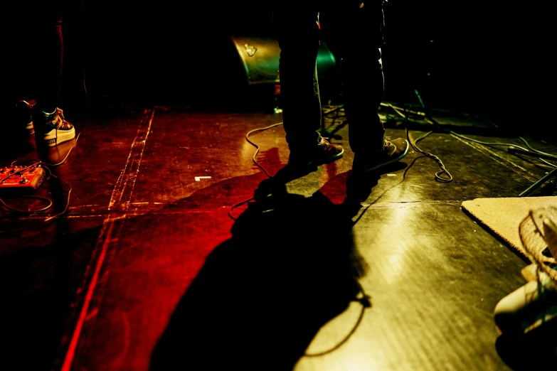 a person standing on a stage with a guitar, flickr, shadow depth, low detailed, red and yellow light, ground level view