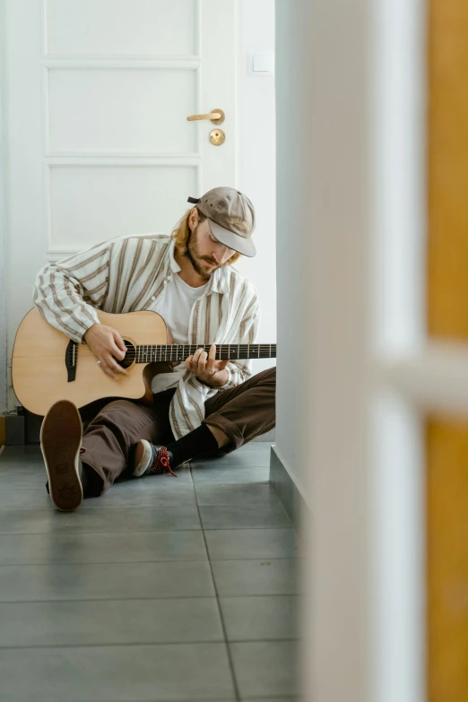 a man sitting on the floor playing a guitar, leaving a room, compassionate, instagram post, concerned