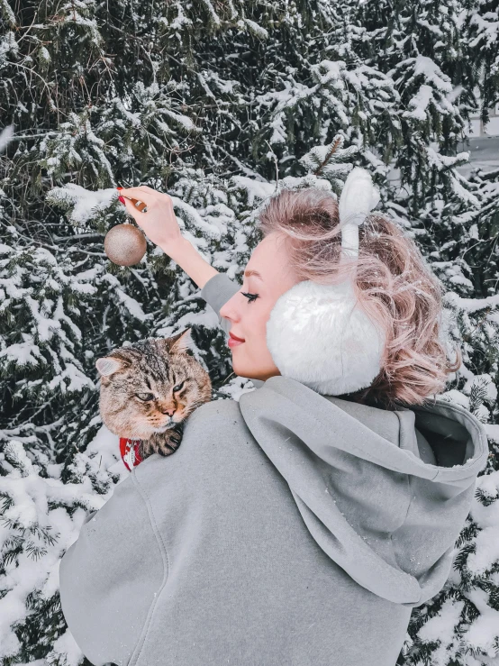 a woman playing with a cat in the snow, a colorized photo, trending on pexels, wearing cat ear headphones, amy sol in the style of, grey and silver, bun )