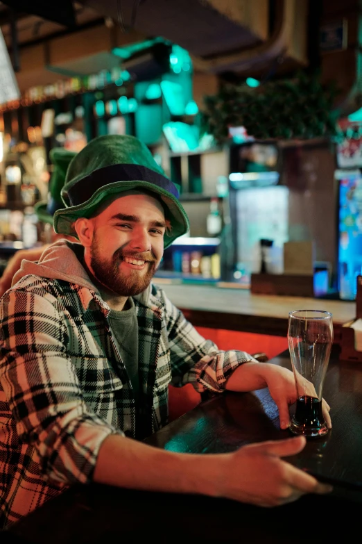 a man sitting at a bar with a glass of wine, green hat, irish genes, hat and hoodie, lgbtq