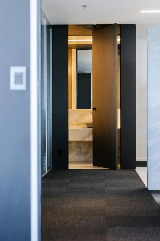 a bath room with a toilet a sink and a mirror, by Harvey Quaytman, unsplash, bauhaus, elevator doors look like a mouth, kyoto studio, exiting from a wardrobe, black marble