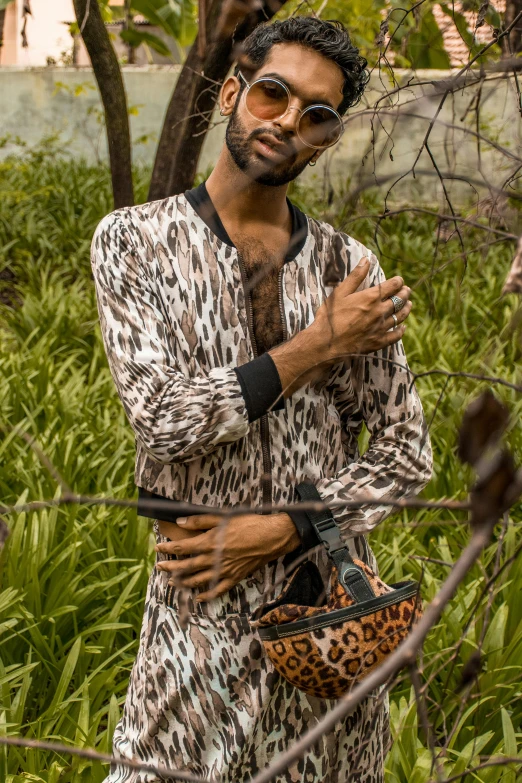 a man standing in a field holding a purse, by Nina Hamnett, trending on pexels, happening, wearing animal skin clothing, brown skin man egyptian prince, at a fashion shoot, on a tree