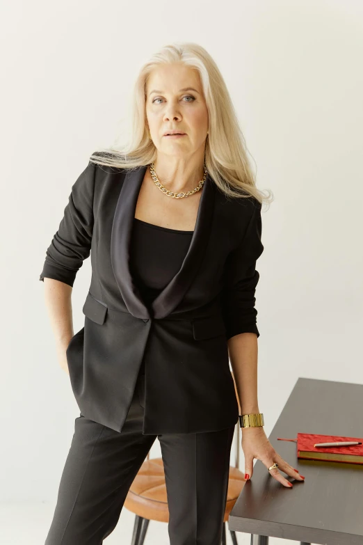 a woman in a black suit standing next to a table, wearing a designer top, suzanne engelberg, profile image, goop