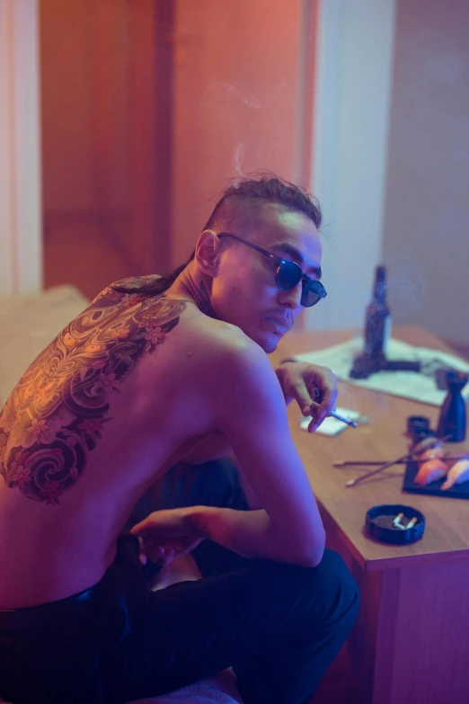 a shirtless man sitting at a desk in front of a computer, a tattoo, inspired by Zhu Da, trending on pexels, hyperrealism, slicked back hair, dr zeus, smoking, long shot from back