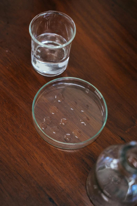 a couple of glasses sitting on top of a wooden table, filled with water, sunken recessed indented spots, detailed product image, detail shot