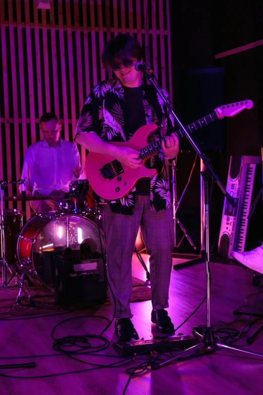 a man that is playing a guitar on a stage, an album cover, pexels, happening, dayglo pink blue, low quality photo, neil blevins and jordan grimmer, loish |