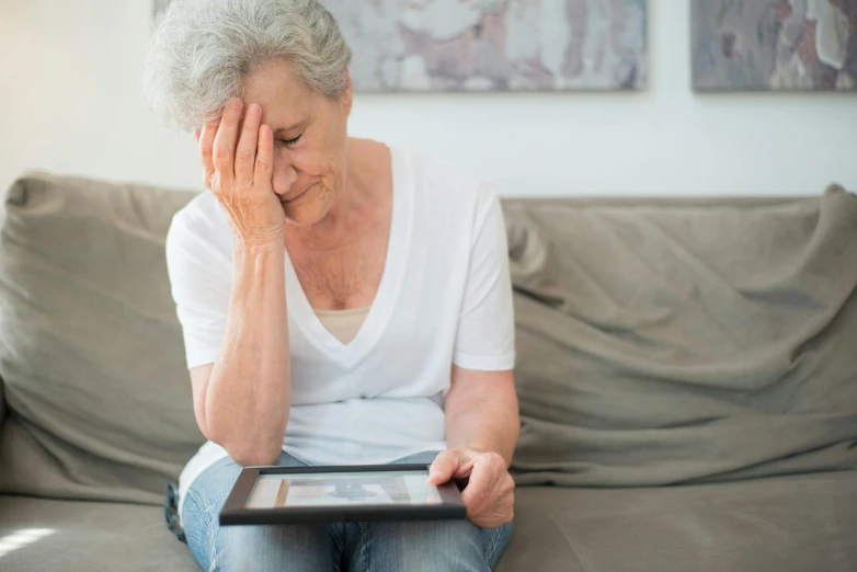 a woman sitting on a couch holding a tablet, pexels, auto-destructive art, dementia, people crying, photograph of april, woman holding sign