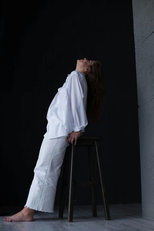 a woman sitting on a stool in a dark room, inspired by Marina Abramović, renaissance, wearing a white shirt, upsidedown, promotional image, pose 4 of 1 6