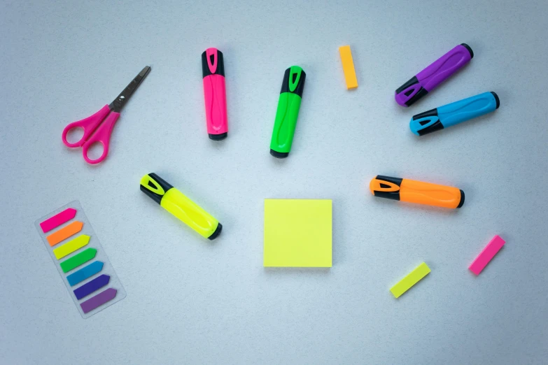 a group of office supplies sitting on top of a table, by Joseph-Marie Vien, pexels, fluorescent colours, permanent marker, on a gray background, ((neon colors))