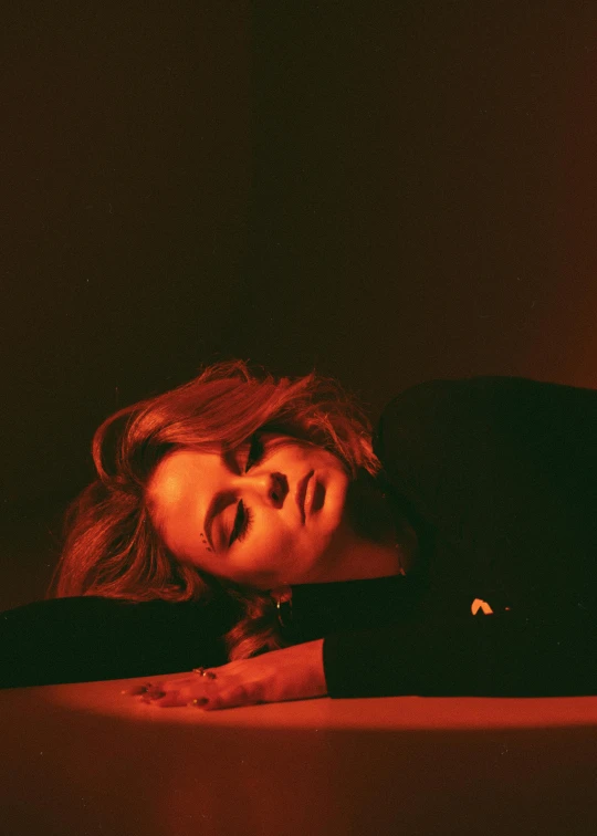 a woman laying on top of a table next to a lit candle, an album cover, inspired by Elsa Bleda, trending on pexels, chloe moretz, thoughtful pose, red light, profile image