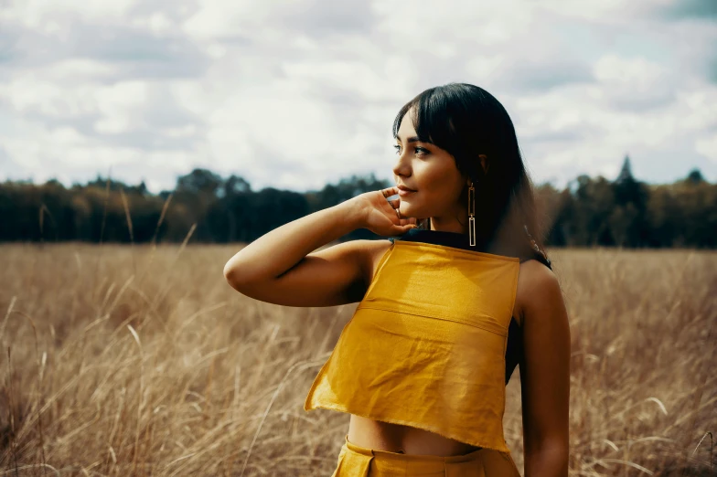 a woman standing in a field of tall grass, an album cover, inspired by Ruth Jên, trending on pexels, happening, wearing yellow croptop, sydney park, profile image, ochre