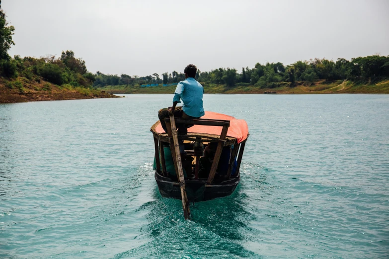 a man sitting on top of a boat in the water, by Joseph Severn, pexels contest winner, hurufiyya, assam tea garden setting, turquoise water, thumbnail, print ready