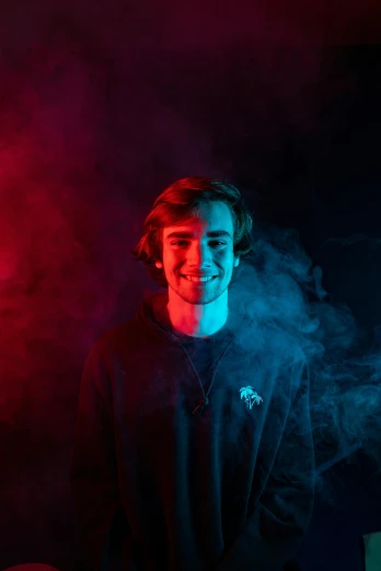a man standing in front of a red and blue light, discord profile picture, connor hibbs, smoke, smiling slightly
