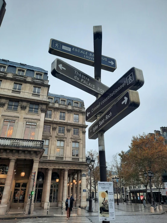 a street sign on a pole in front of a building, by Sebastian Vrancx, unsplash, paris school, on a great neoclassical square, taken on iphone 14 pro, books all over the place, 2 5 6 x 2 5 6 pixels