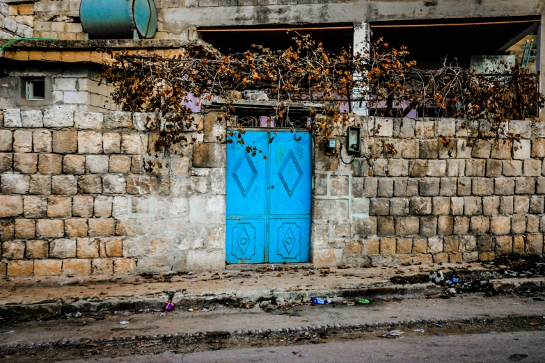 a blue door sitting on the side of a building, by Ibrahim Kodra, les nabis, photo of poor condition, getty images, sukkot, scattered rubbish and debris