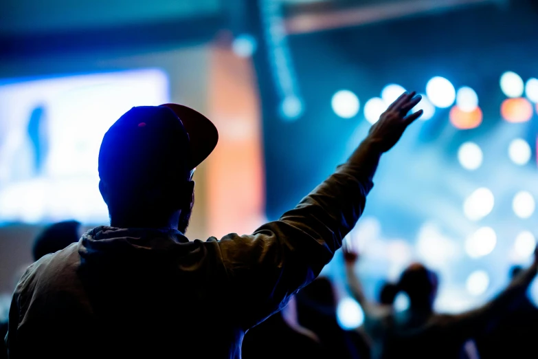 a man standing in front of a crowd at a concert, pexels, doing a prayer, videogame still, raising an arm, church background