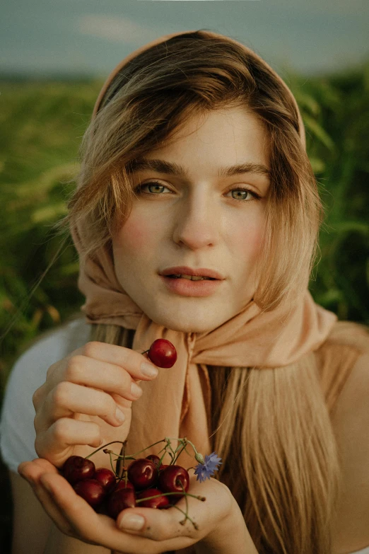 a woman holding a bunch of cherries in her hands, a colorized photo, by irakli nadar, trending on pexels, renaissance, wearing a head scarf, a blond, portrait androgynous girl, in a field