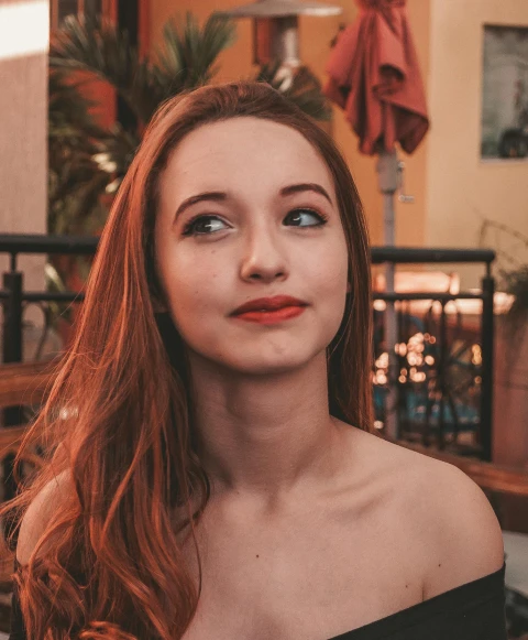 a woman with long red hair wearing a black dress, inspired by Elsa Bleda, trending on pexels, twitch streamer, portrait sophie mudd, grinning lasciviously, distant photo