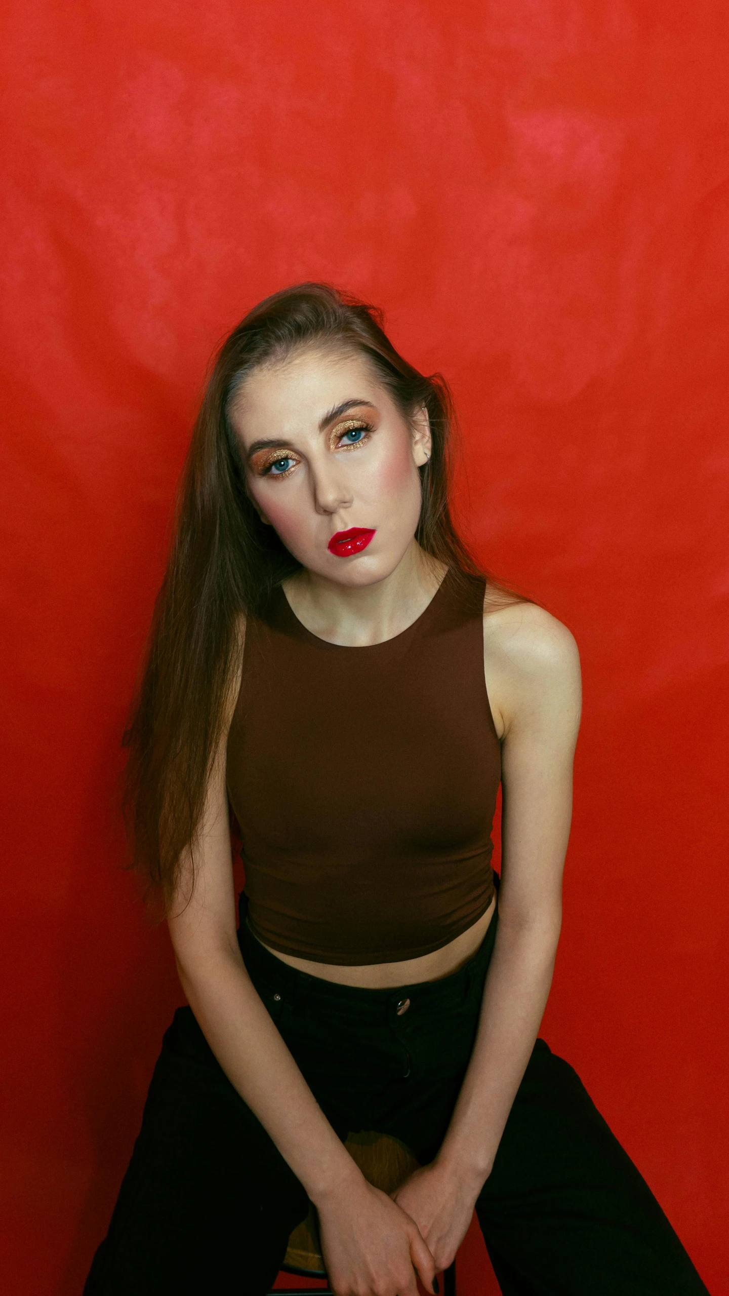 a woman sitting on a skateboard in front of a red wall, an album cover, inspired by Julia Pishtar, trending on pexels, both have red lips, wearing a black cropped tank top, 15081959 21121991 01012000 4k, headshot photograph