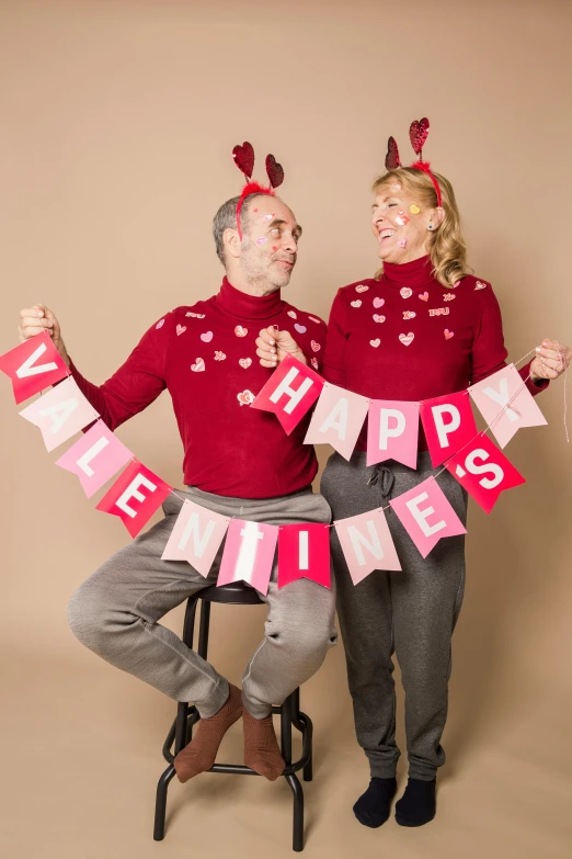 a man and a woman standing next to each other, a photo, by Valentine Hugo, pexels, folk art, red sweater and gray pants, red pennants, fun pose, antennae