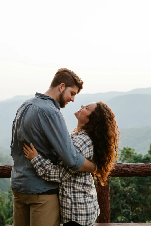 a man and a woman standing next to each other, pexels contest winner, hills in the background, curls, cuddling, attractive man