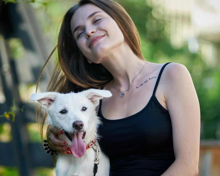 a woman holding a white dog in her arms, pexels contest winner, she is wearing a black tank top, avatar image, wearing collar, 2 5 yo