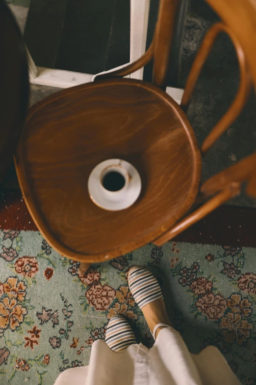 a person standing on a rug next to a chair, by Matthias Stom, trending on unsplash, coffee cup, brown holes, porcelain, stains