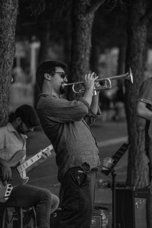 a group of men playing instruments in a park, a black and white photo, pexels contest winner, photorealism, horns under his cheek, 15081959 21121991 01012000 4k, at a city street, (night)