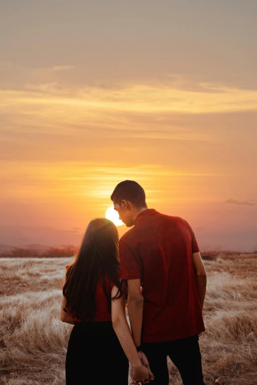 a couple standing next to each other in a field, by Robbie Trevino, pexels contest winner, romanticism, redpink sunset, ( ( ( ( kauai ) ) ) ), handsome, brown