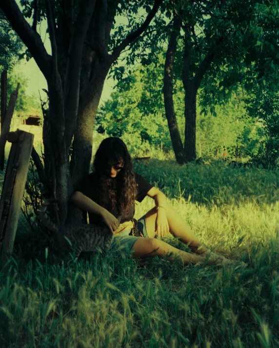 a woman sitting under a tree reading a book, a polaroid photo, inspired by Elsa Bleda, romanticism, still from a music video, the grass, instagram photo, album cover