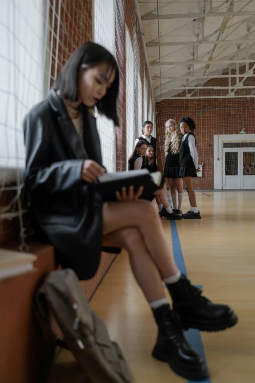 a girl sitting on a bench reading a book, an album cover, trending on pexels, vancouver school, in school hallway, group of people in a dark room, dressed as schoolgirl, looking at the ground