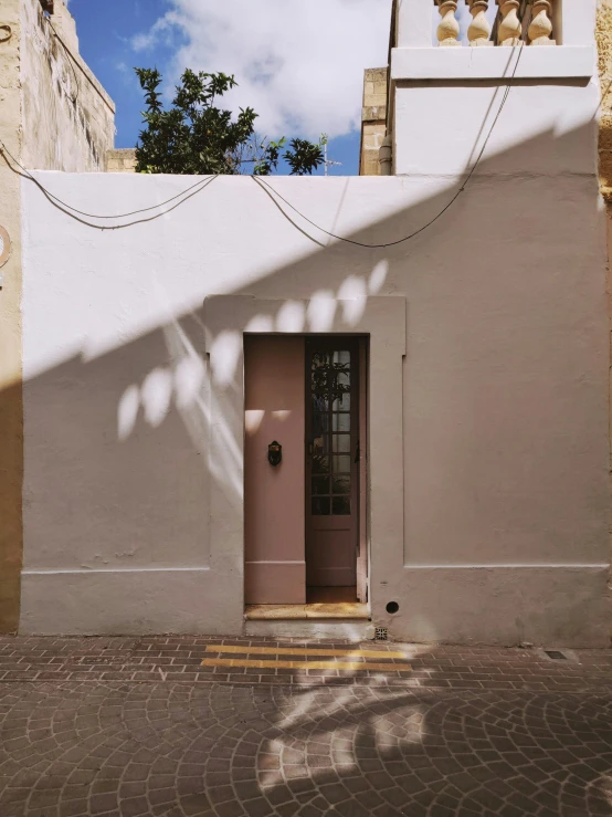 a red fire hydrant sitting in front of a white building, by Nathalie Rattner, pexels contest winner, light and space, pink door, shady alleys, architectural digest photo, light - brown wall