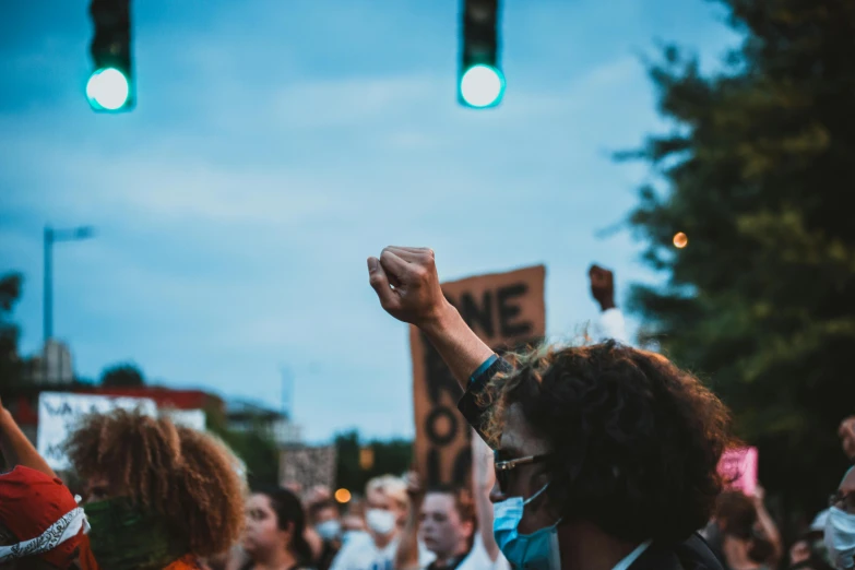 a group of people that are standing in the street, trending on pexels, renaissance, protest, summer night, a person standing in front of a, raised fist